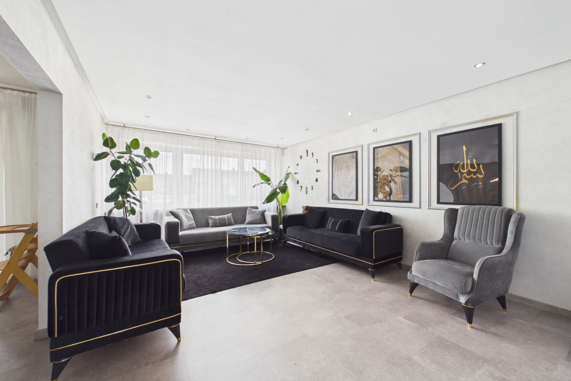 Modernes Wohnzimmer mit drei Sofas, Sessel, Pflanzen und drei Bildern an der Wand.