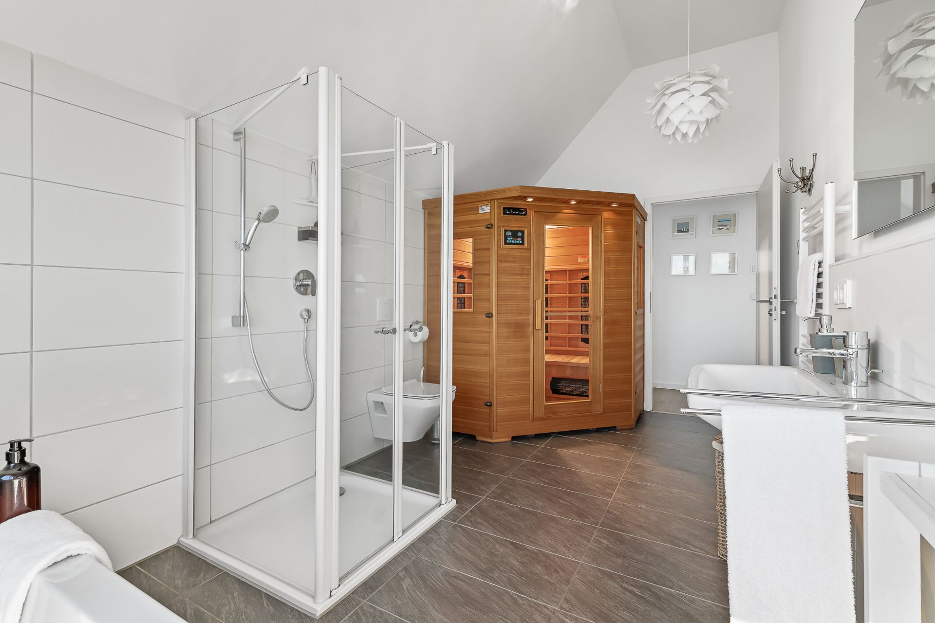 Helles Badezimmer mit Dusche, Sauna, Waschbecken und modernem Dekor.