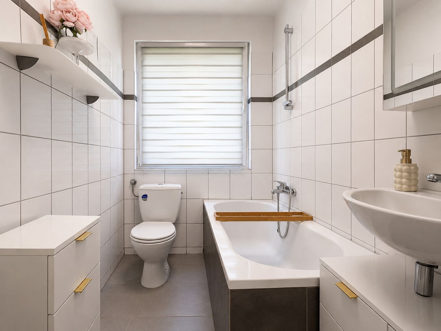 Modernes Badezimmer mit Badewanne, WC, Waschbecken und weißen Fliesen.