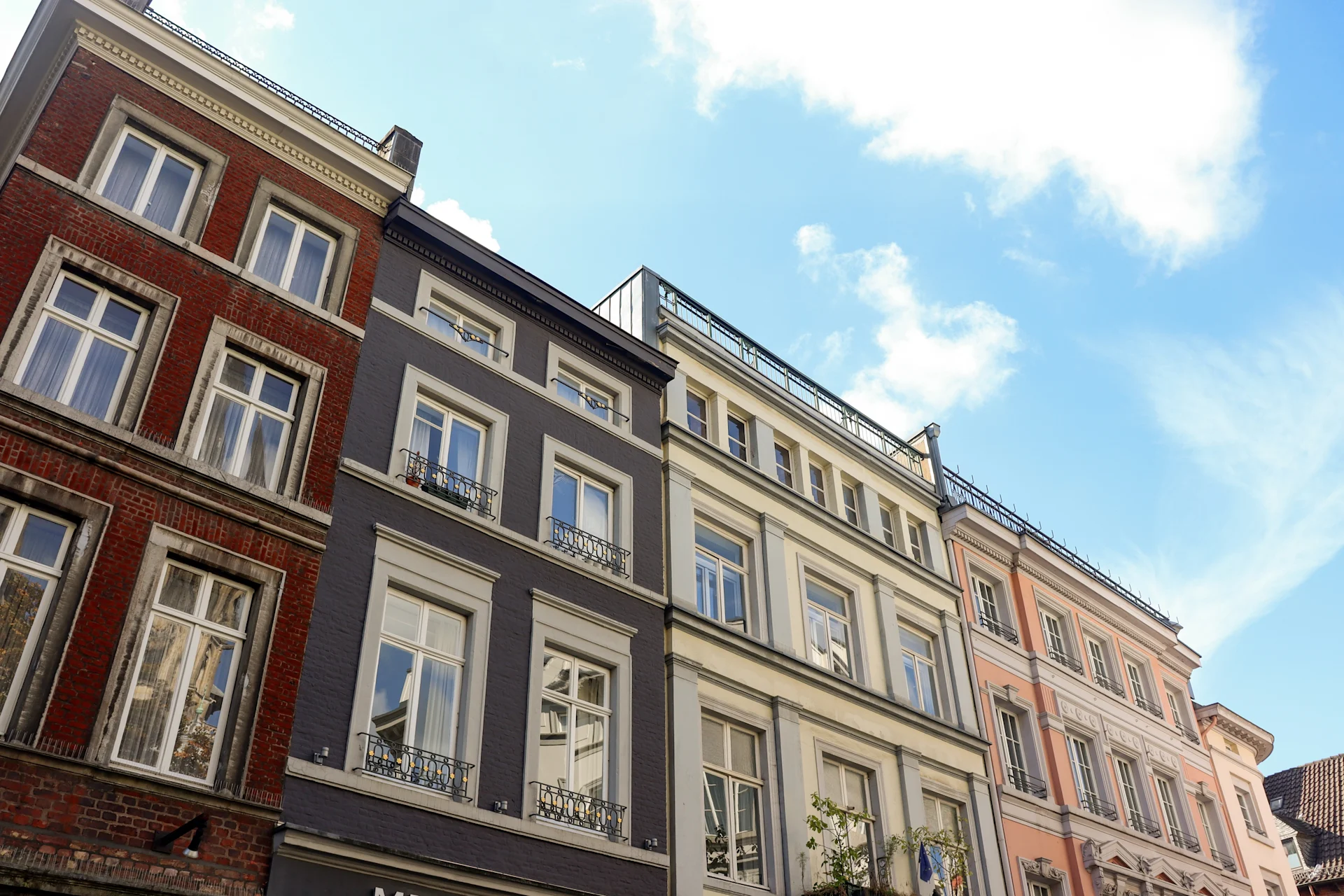 Mehrere bunte Wohnhäuser mit großen Fenstern unter blauem Himmel.