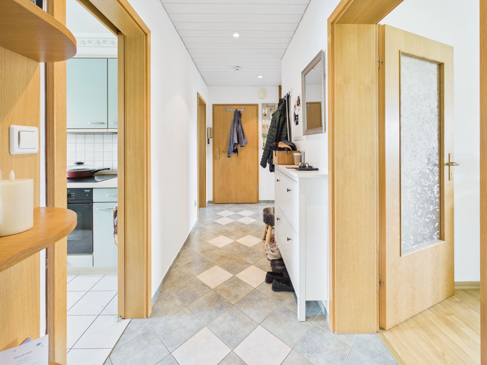 Heller Flur mit Fliesenboden, Garderobe, Spiegel und Türen zu weiteren Räumen.
