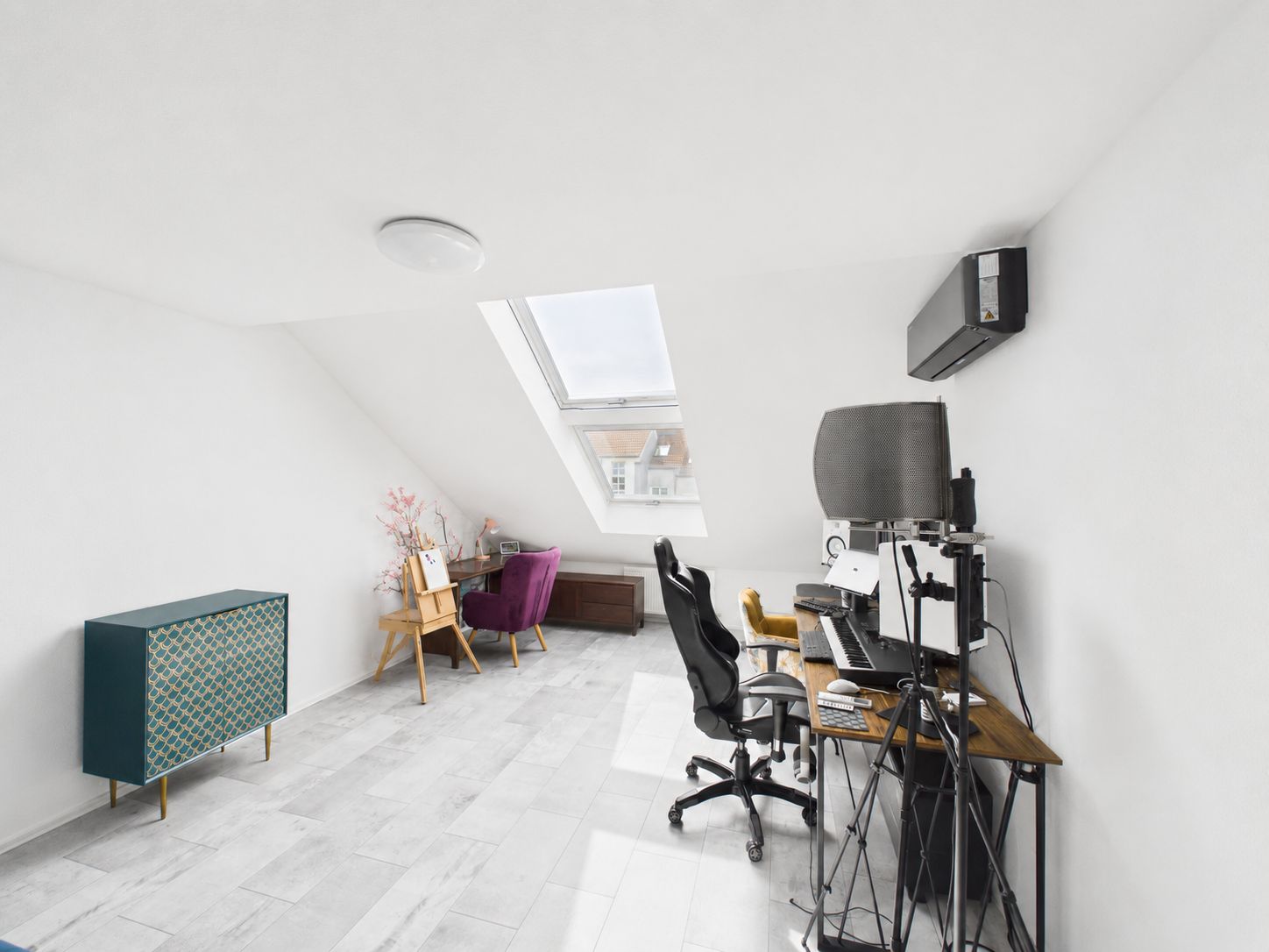Helles Arbeitszimmer mit Schreibtisch, Stuhl, Kommode und Dachfenster.