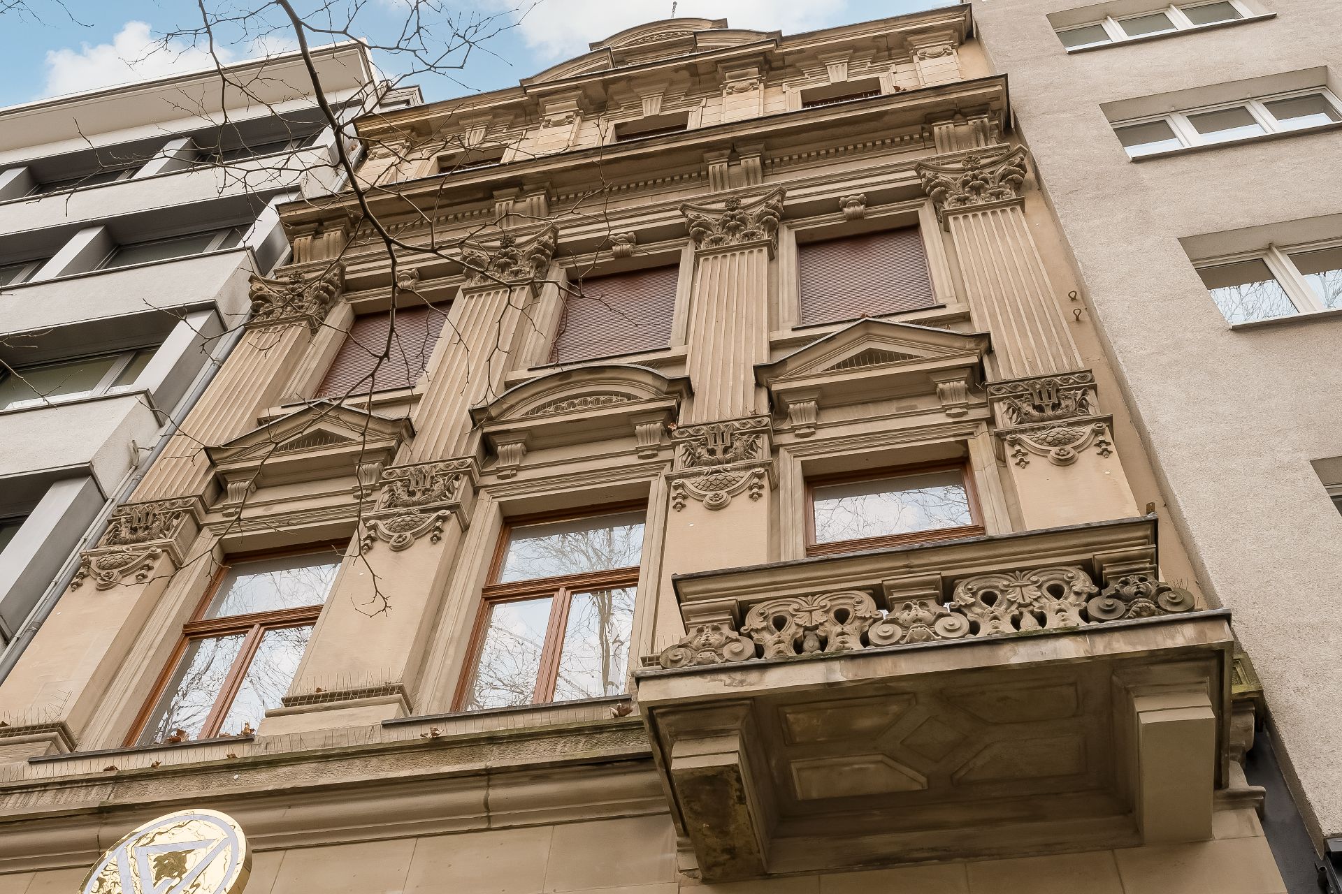 Fassade eines alten Wohngebäudes mit dekorativen Säulen und Balkon.