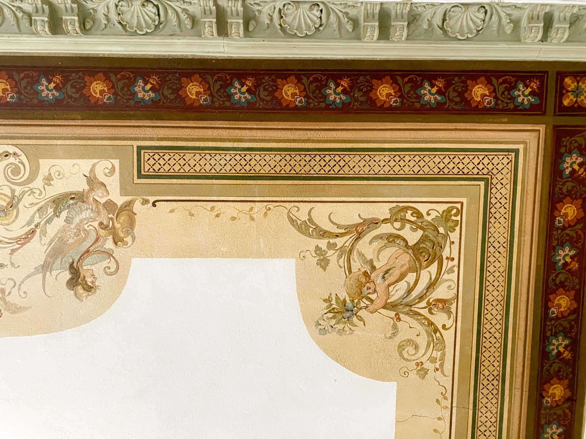 Verzierte Zimmerdecke mit floralen Mustern und gemaltem Dekor in kräftigen Farben.