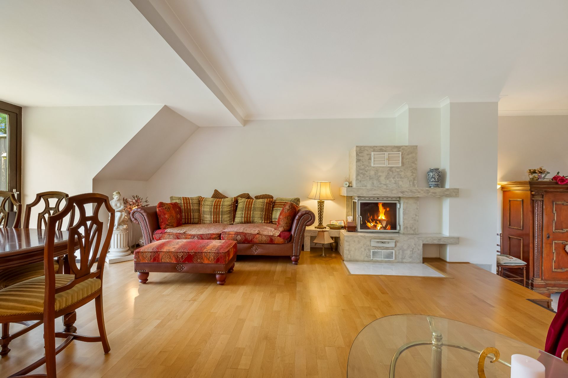 Wohnzimmer mit gemustertem Sofa, Holztisch, Kamin und Holzfußboden.