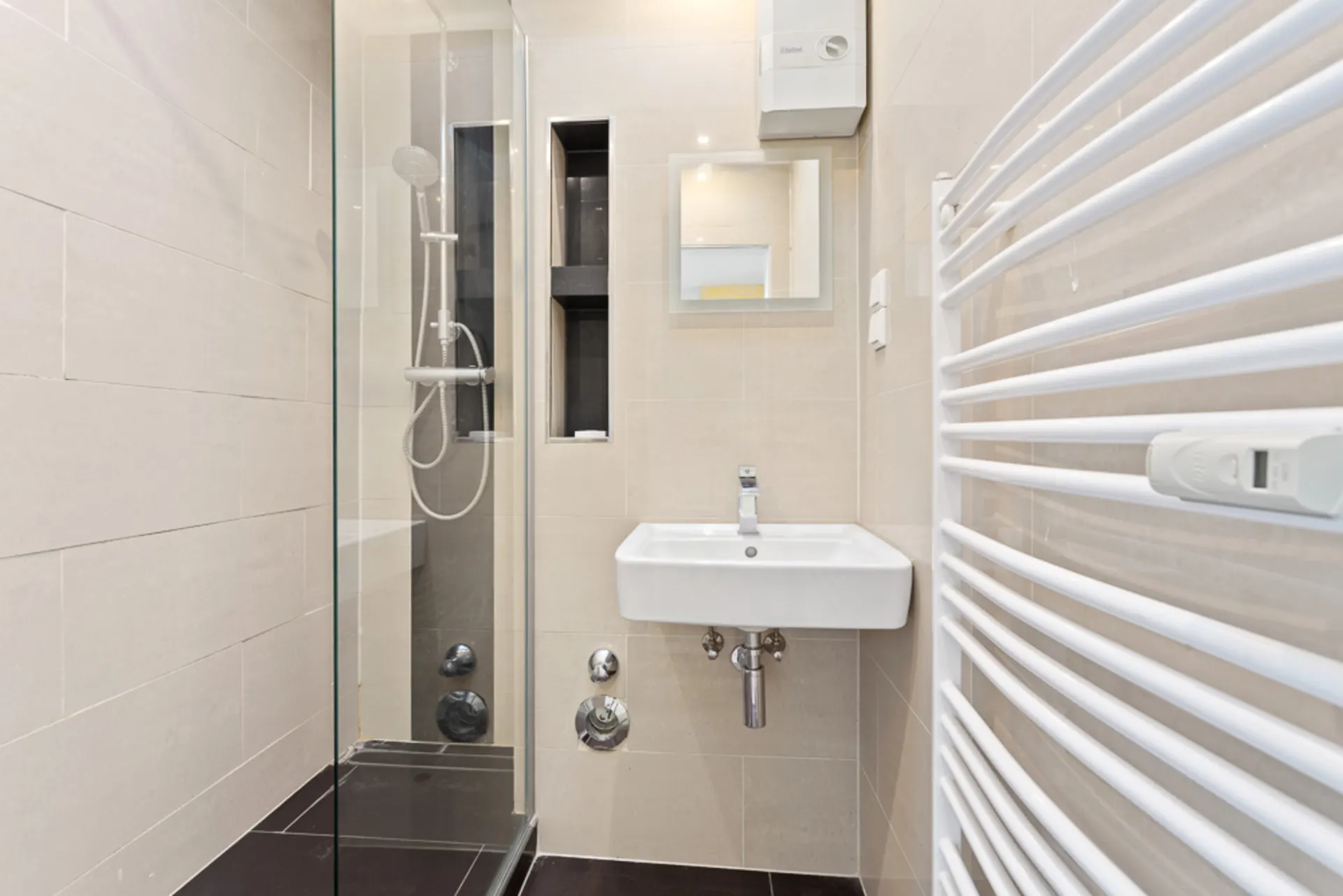 Modernes Badezimmer mit Dusche, Waschbecken, Spiegel und weißem Handtuchheizkörper.