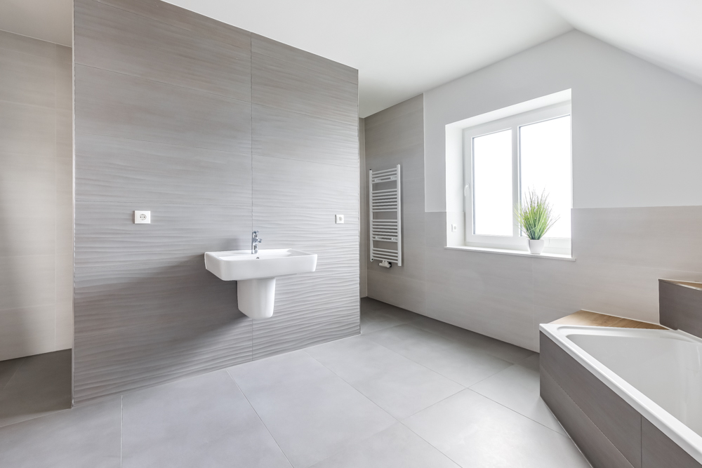 Modernes, helles Badezimmer mit Waschbecken, Badewanne, Fenster und Handtuchheizkörper.
