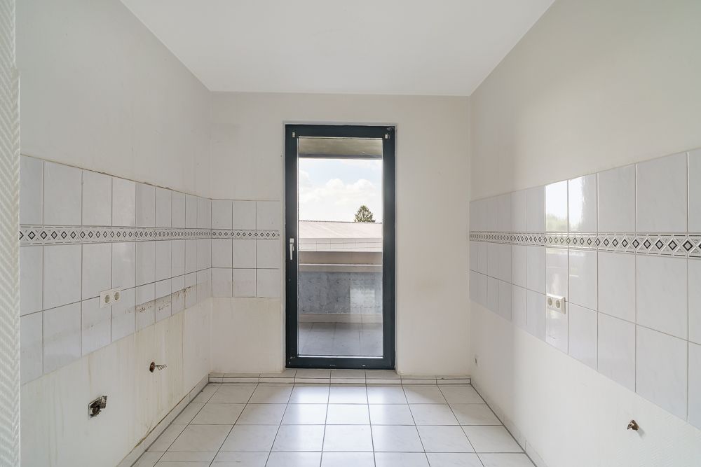 Leerer, gefliester Raum mit Tür zu einem Balkon oder Terrasse.