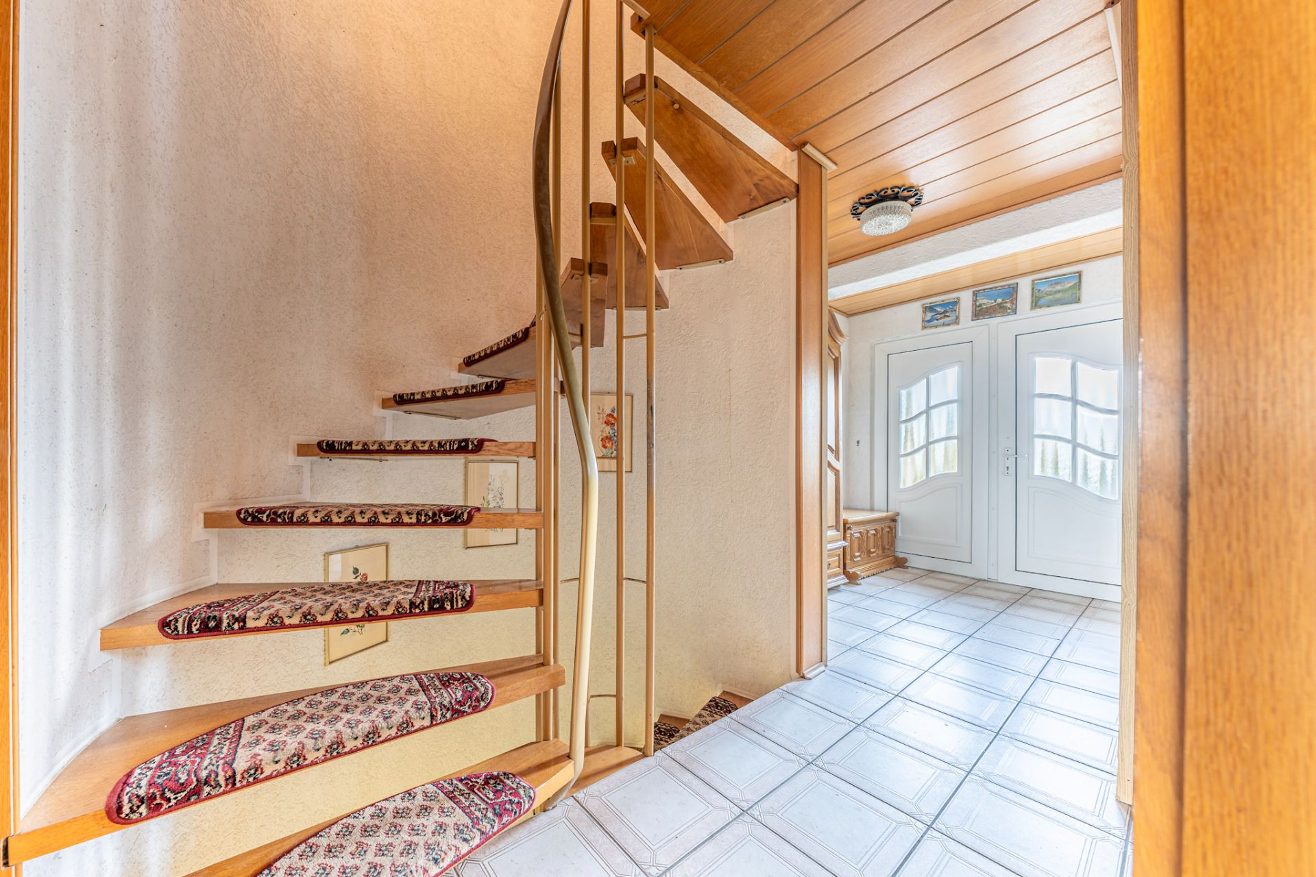 Eingangsbereich mit Wendeltreppe, Teppichstufen und weißen Doppeltüren.