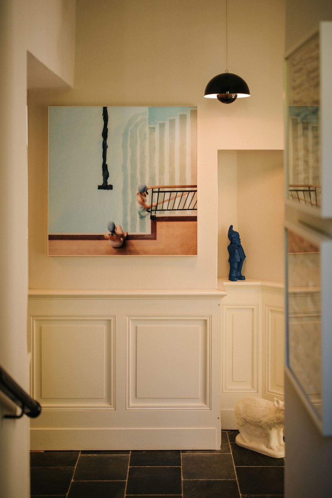 Flur mit Bild an der Wand, einer blauen Figur und einer weißen Skulptur auf dem Boden.