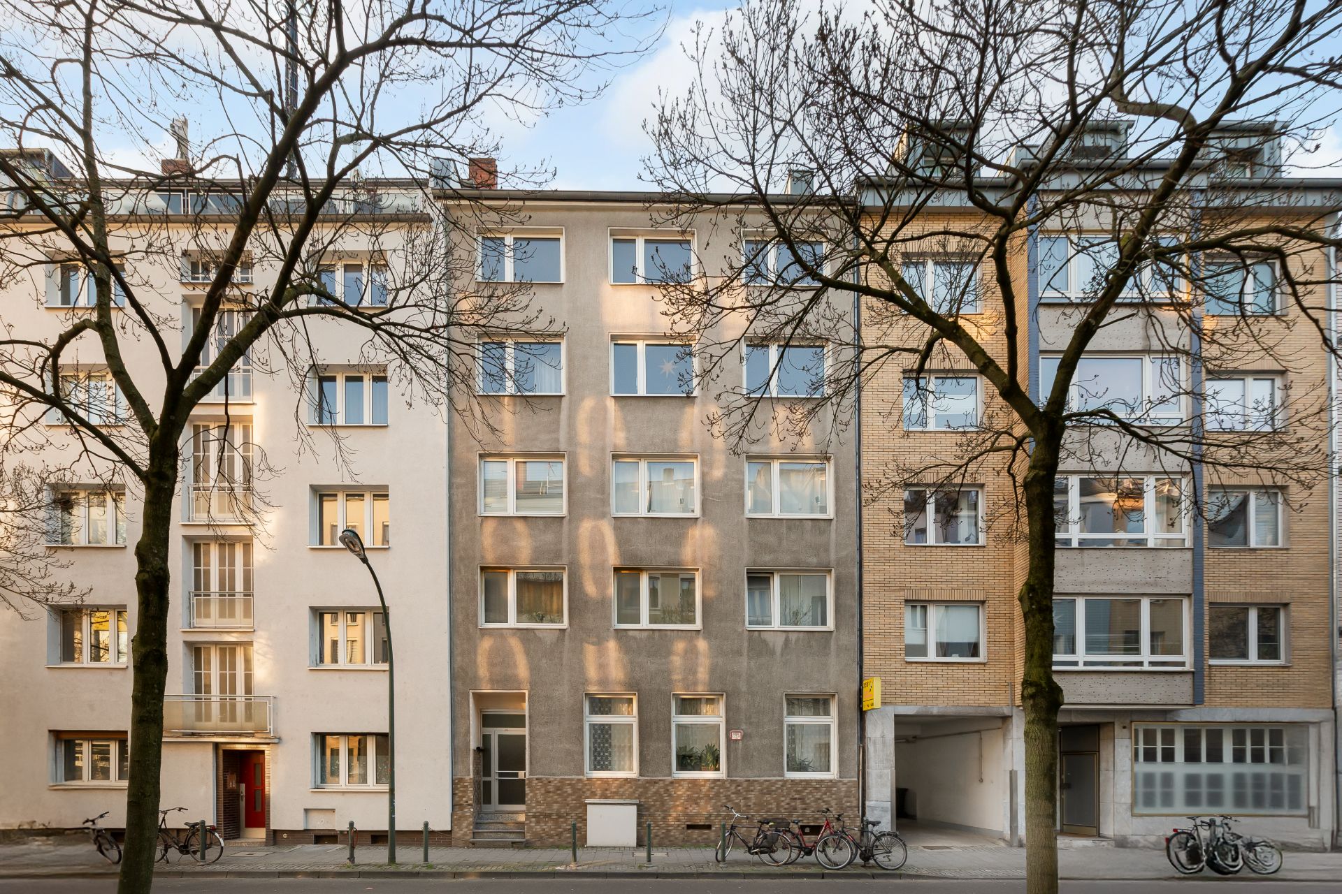 Mehrstöckiges Wohnhaus mit großen Fenstern und Fahrrädern vor dem Eingang.