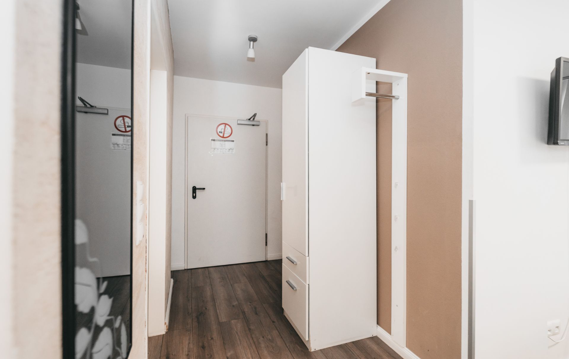 Heller Flur mit weißem Schrank, brauner Wand und Holzboden.