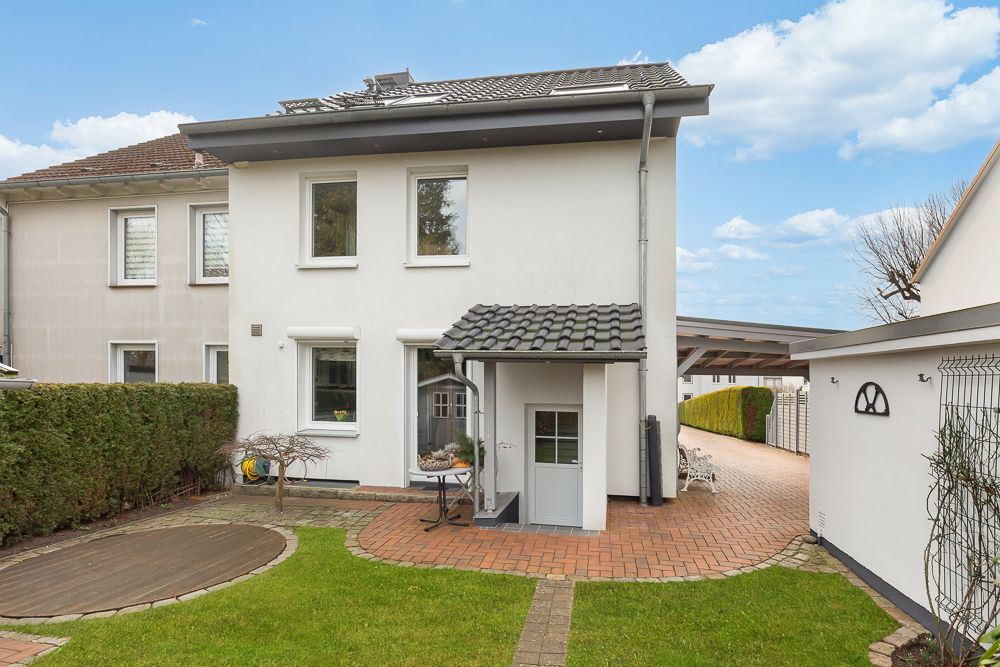 Zweistöckiges Wohnhaus mit kleinem Garten, Terrasse und Weg aus Pflastersteinen.