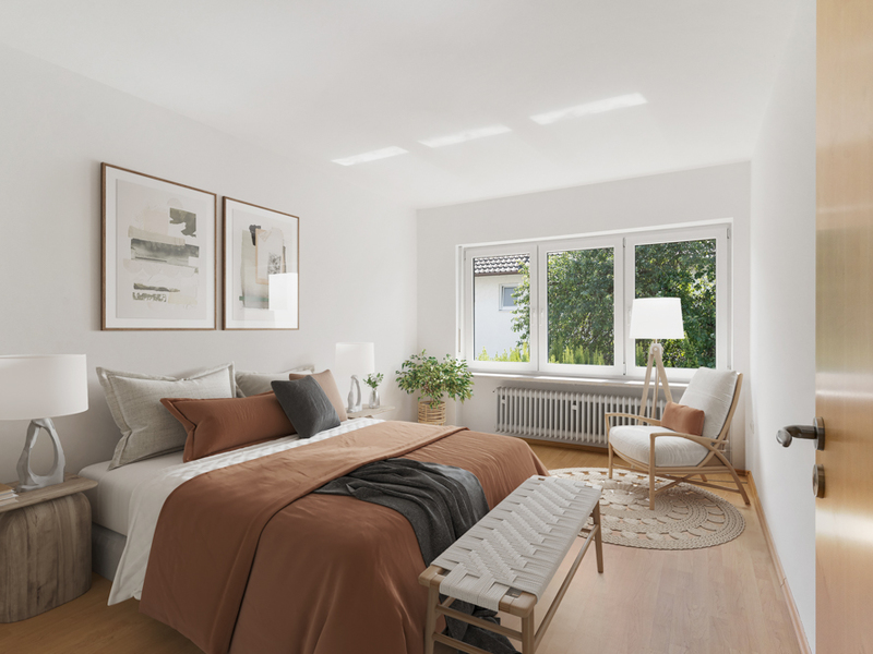 Helles Schlafzimmer mit großem Bett, zwei Nachttischen, Stuhl und Pflanzen vor einem Fenster.