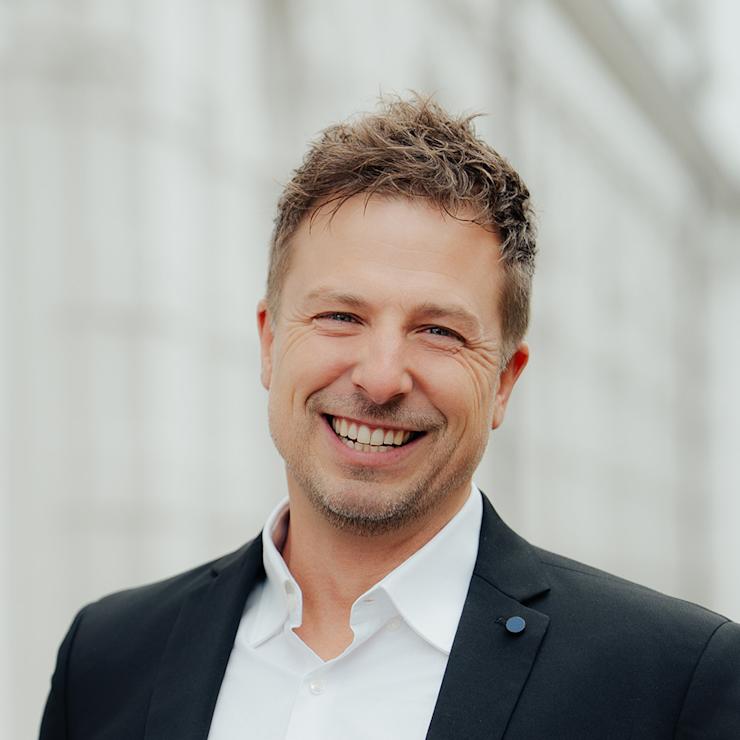 Ein Mann im Anzug lächelt in die Kamera.