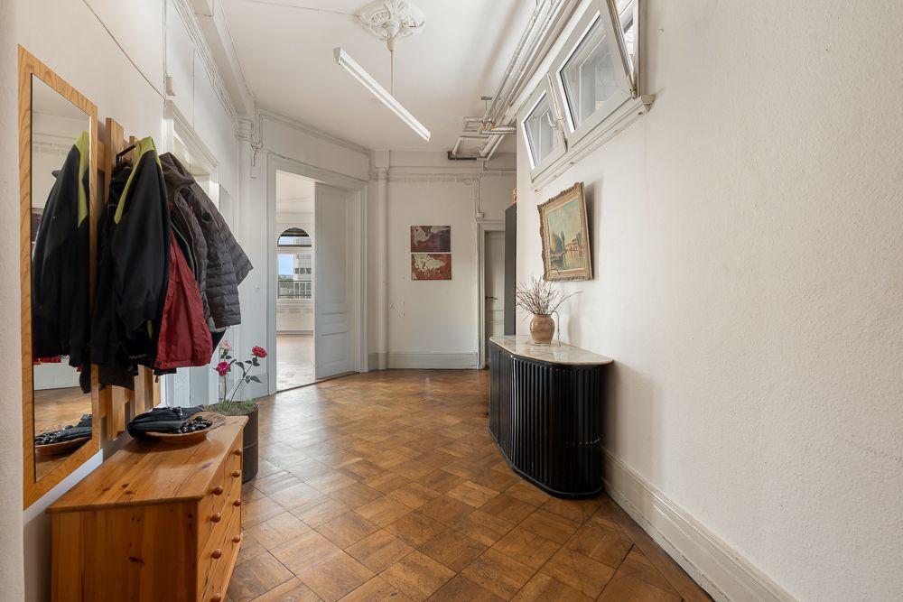 Heller Flur mit Holzkommode, Spiegel, Garderobe und Bildern an der Wand.