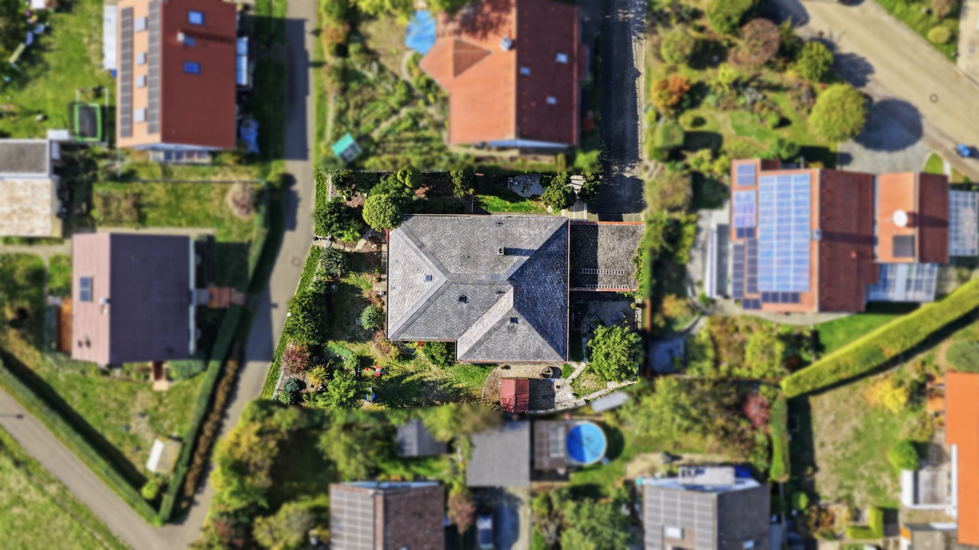 Luftaufnahme eines Wohnhauses mit Garten, umgeben von weiteren Häusern und Straßen.