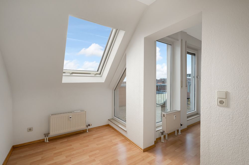 Heller Raum mit Dachfenster, großen Fenstern und Laminatboden.