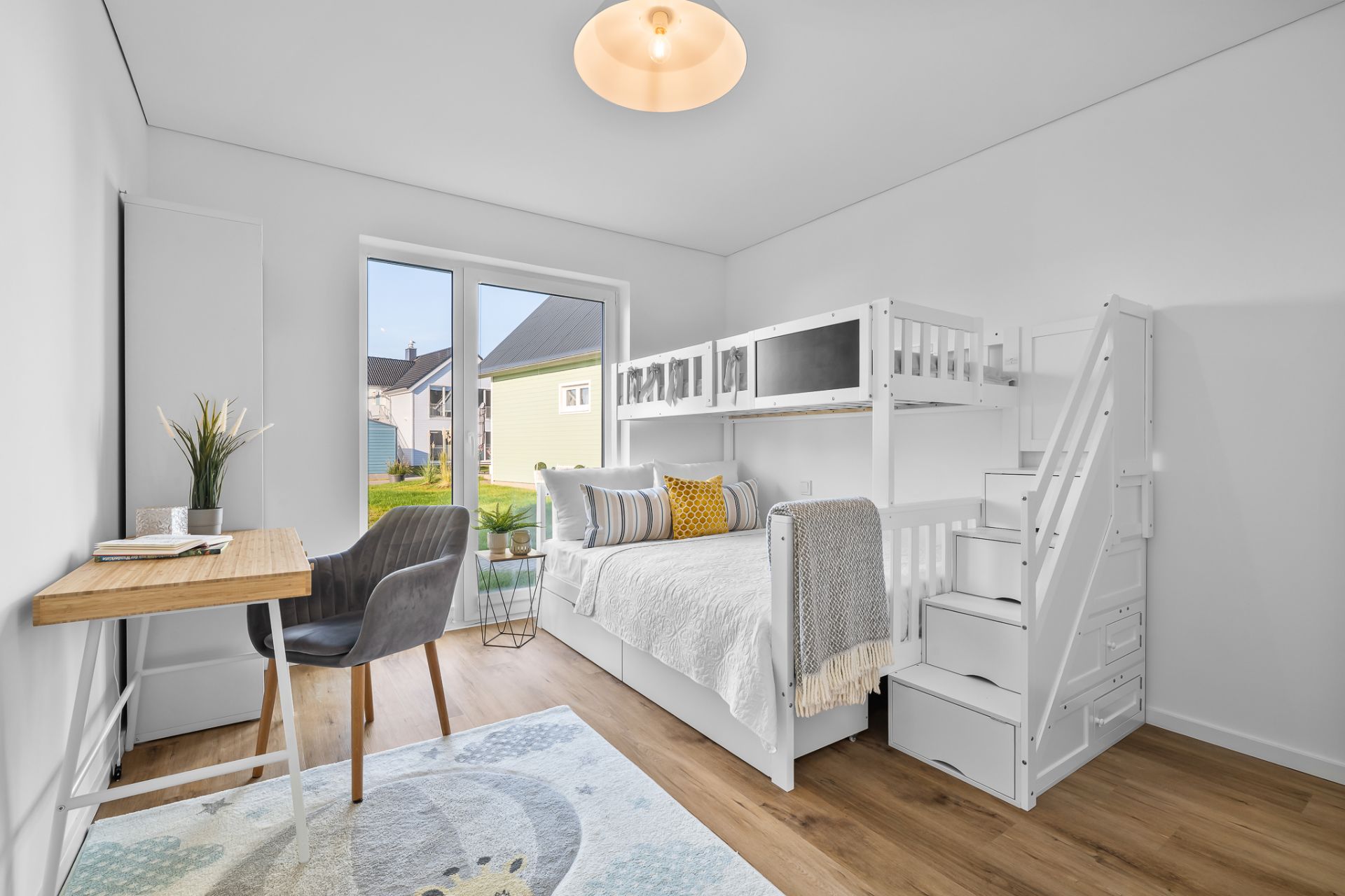 Helles Kinderzimmer mit Hochbett, Schreibtisch, Teppich und großem Fenster zum Garten.