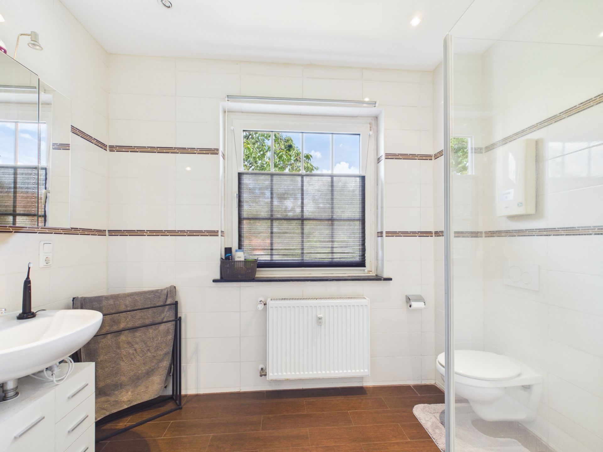 Modernes Badezimmer mit Fenster, Waschbecken, Toilette und Dusche.