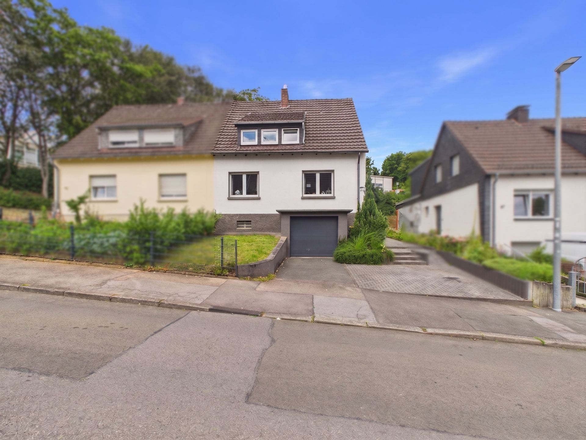 Doppelhaushälfte mit Vorgarten, Auffahrt und Garage an einer ruhigen Straße.