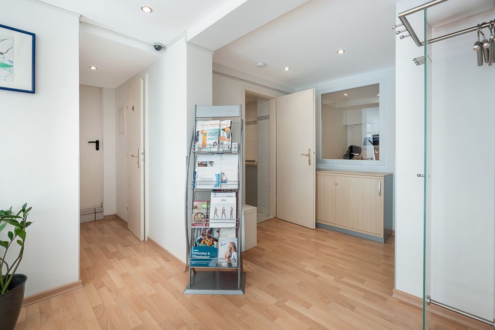 Heller Flur mit Holzfußboden, Zeitschriftenständer, offener Tür und kleinem Schrank.