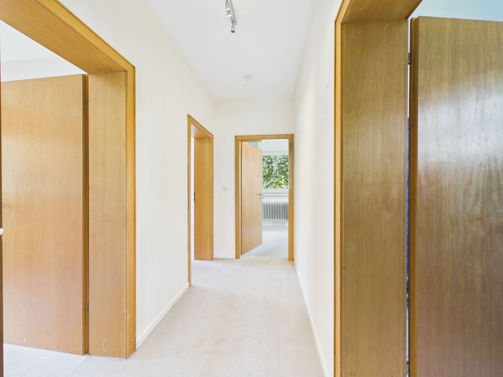 Heller Flur mit mehreren Holztüren in einer Wohnung.