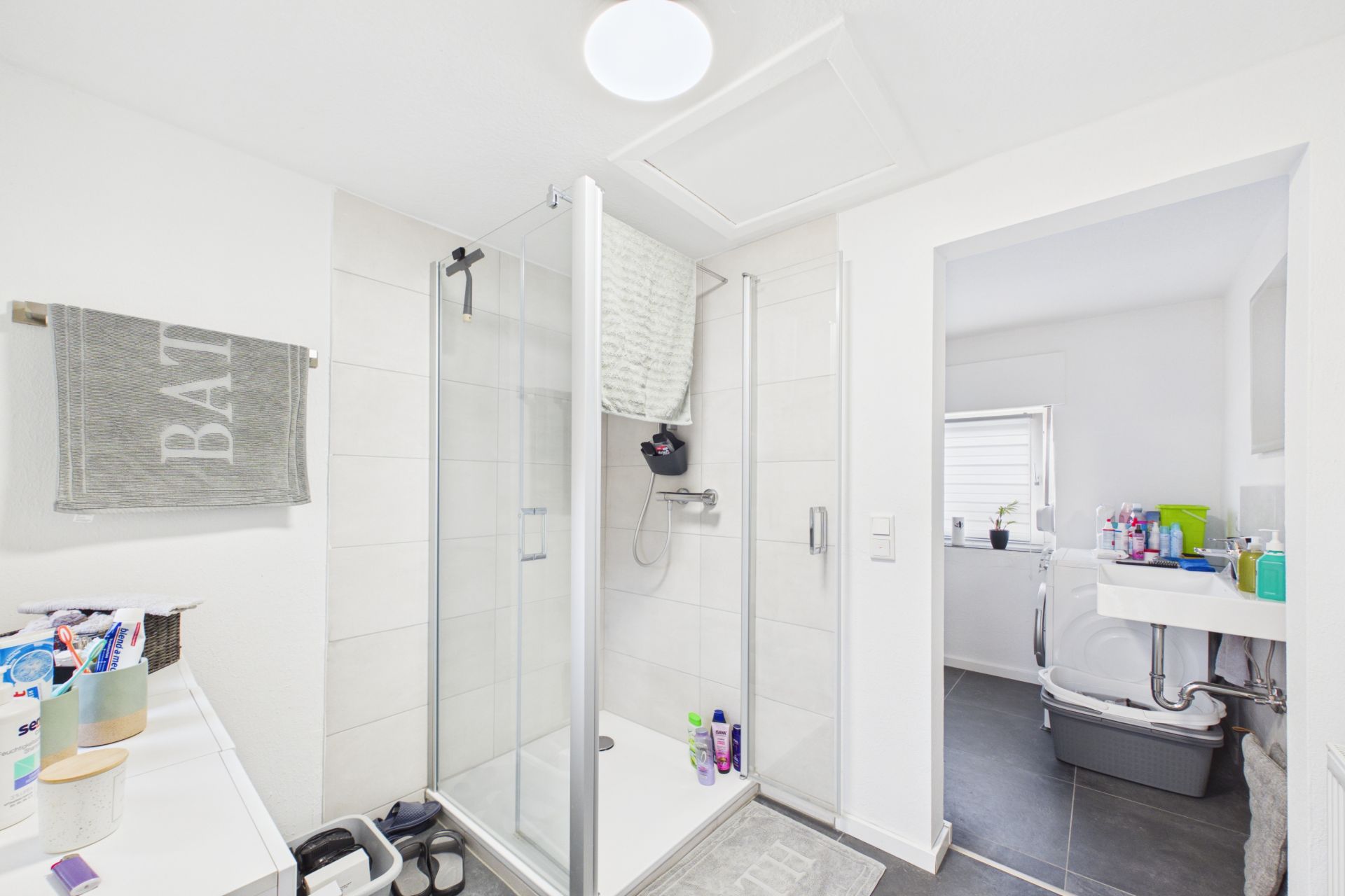 Helles Badezimmer mit Dusche, Handtuch, Waschbecken und Badezimmerzubehör.