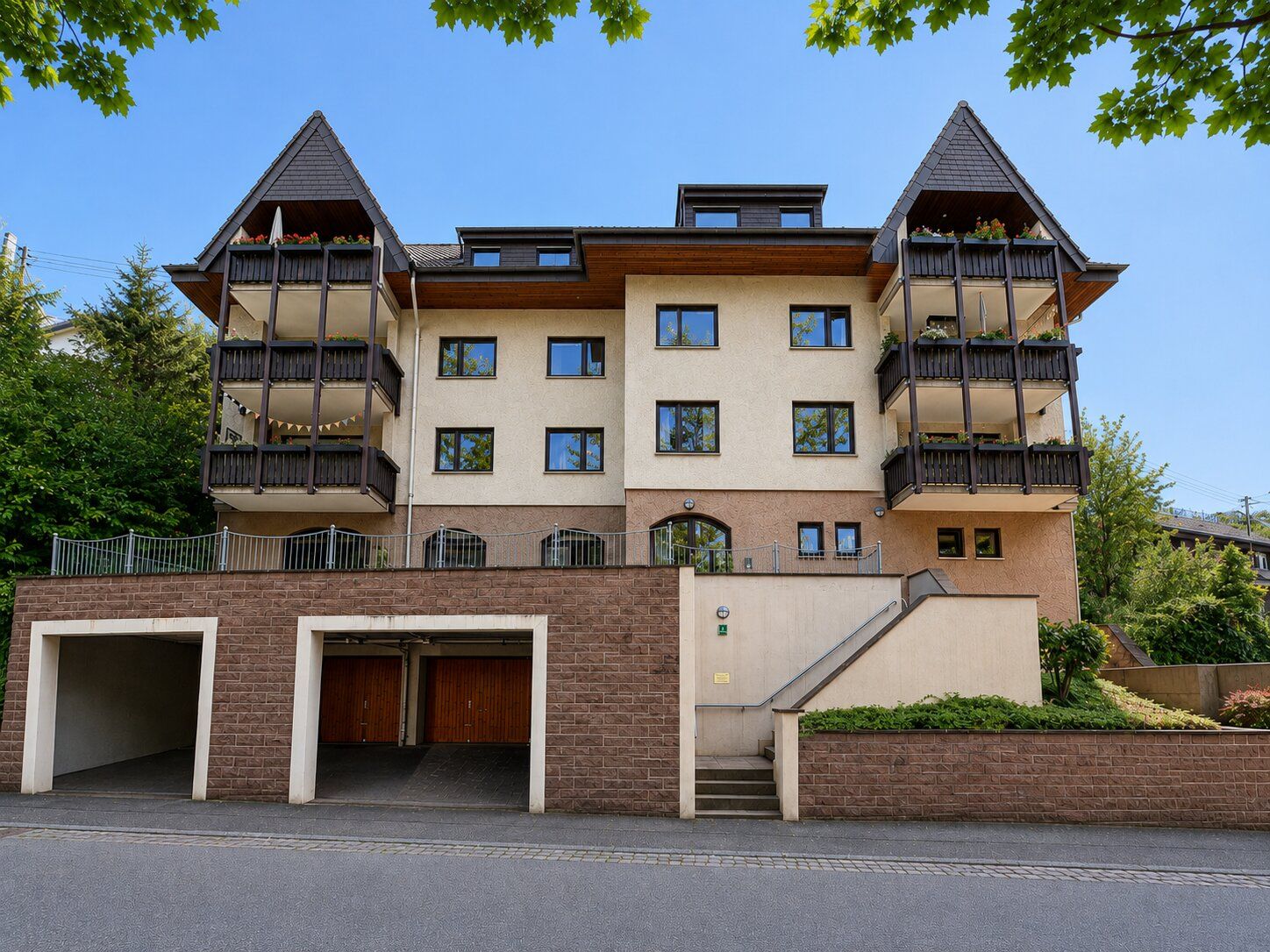 Mehrfamilienhaus mit Balkonen, Garagen und Treppenaufgang im Vordergrund.