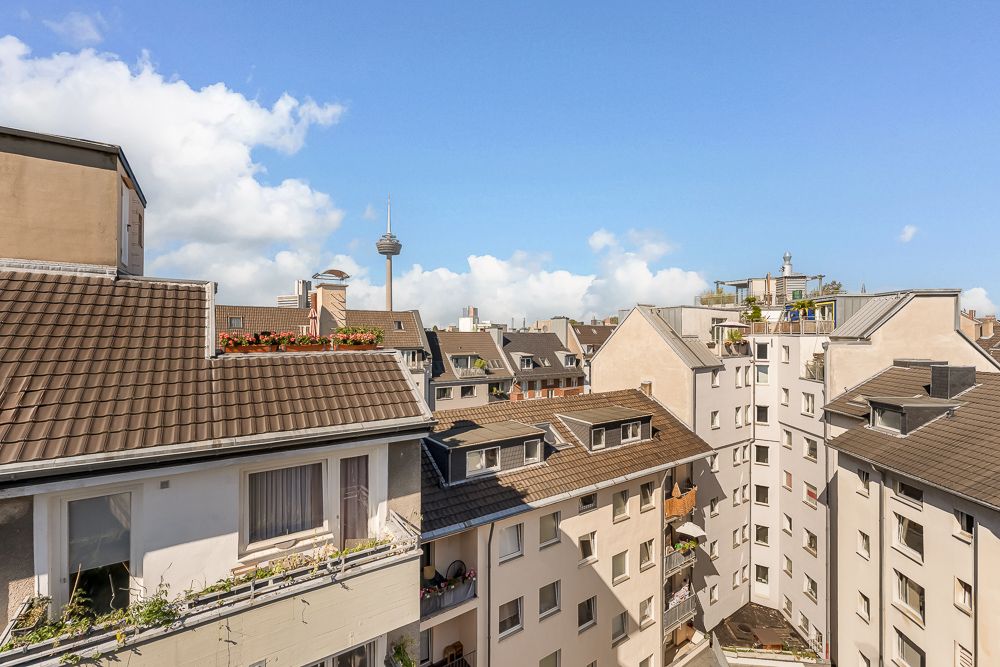 Blick auf mehrere Wohngebäude mit Balkonen und Blumen, im Hintergrund ein Fernsehturm.