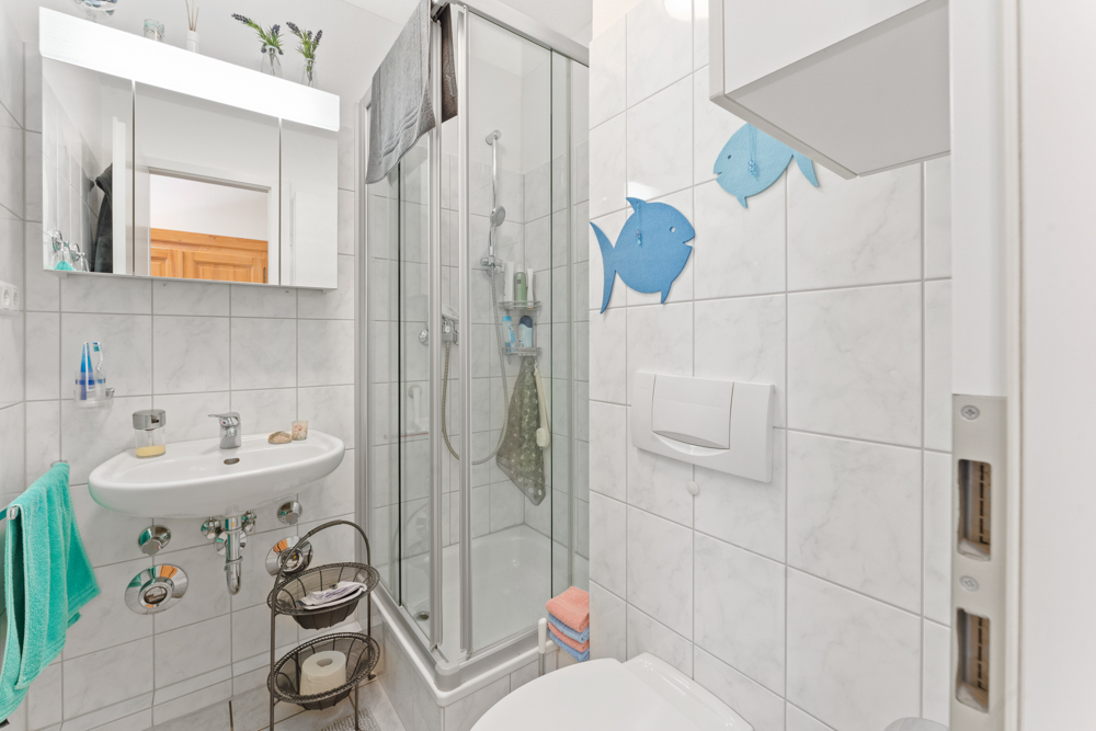 Modernes, kleines Badezimmer mit Dusche, Waschbecken, WC und Dekorationen in Fischform an der Wand.