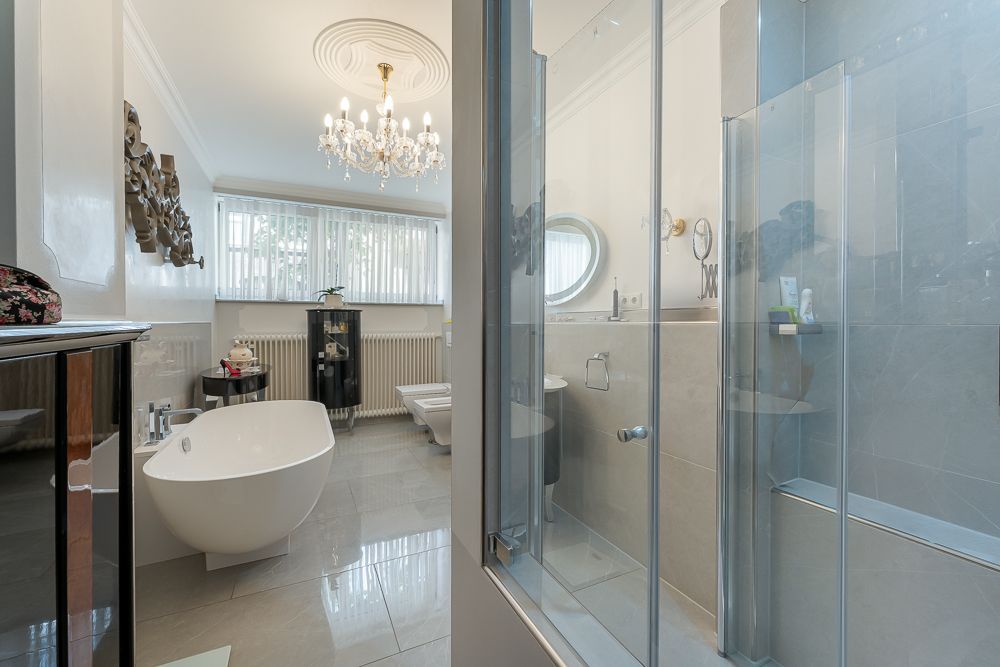 Modernes Badezimmer mit freistehender Badewanne, Dusche, Bidet und Kronleuchter.