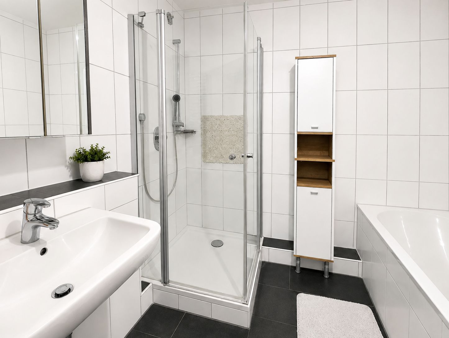 Modernes Badezimmer mit Dusche, Waschbecken, Badewanne und Schrank auf weißen Fliesen.