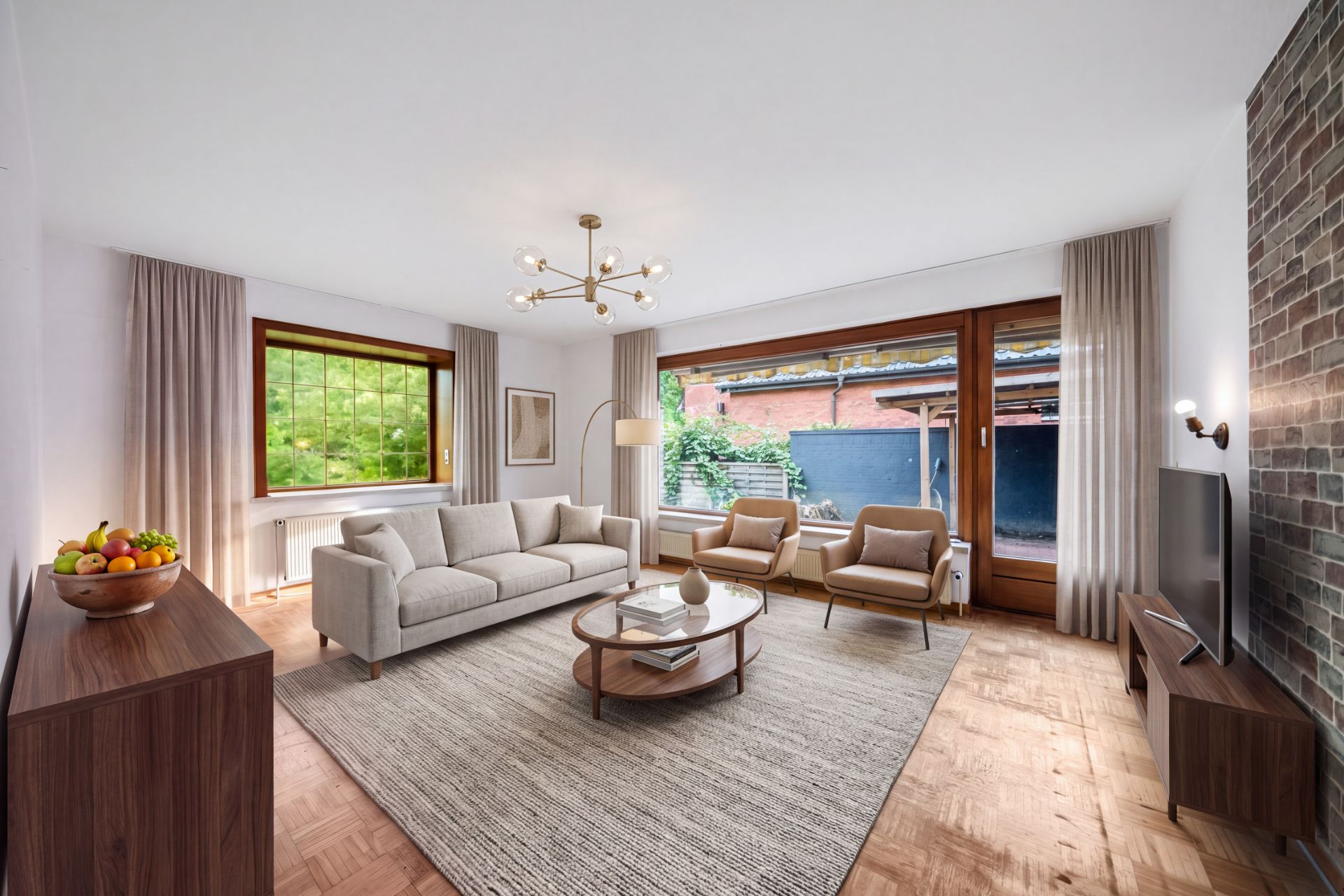 Helles Wohnzimmer mit Sofa, Sesseln, Couchtisch, Teppich und großem Fenster zum Garten.