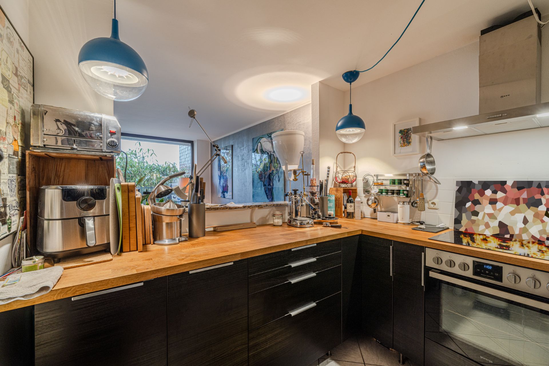 Moderne Küche mit Holzarbeitsplatte, Geräten und Hängelampen.