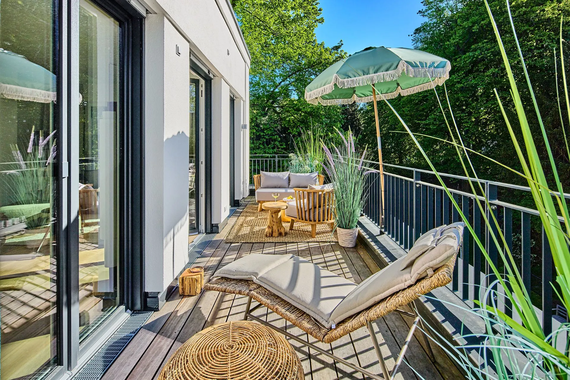 Balkon mit Liegestuhl, Sonnenschirm, Pflanzen und gemütlicher Sitzecke an einer modernen Wohnung.
