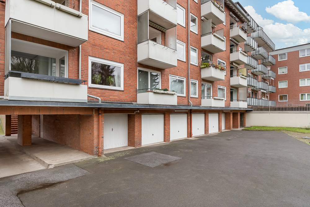 Mehrstöckiges Wohngebäude mit Balkonen und Garagen im Erdgeschoss.