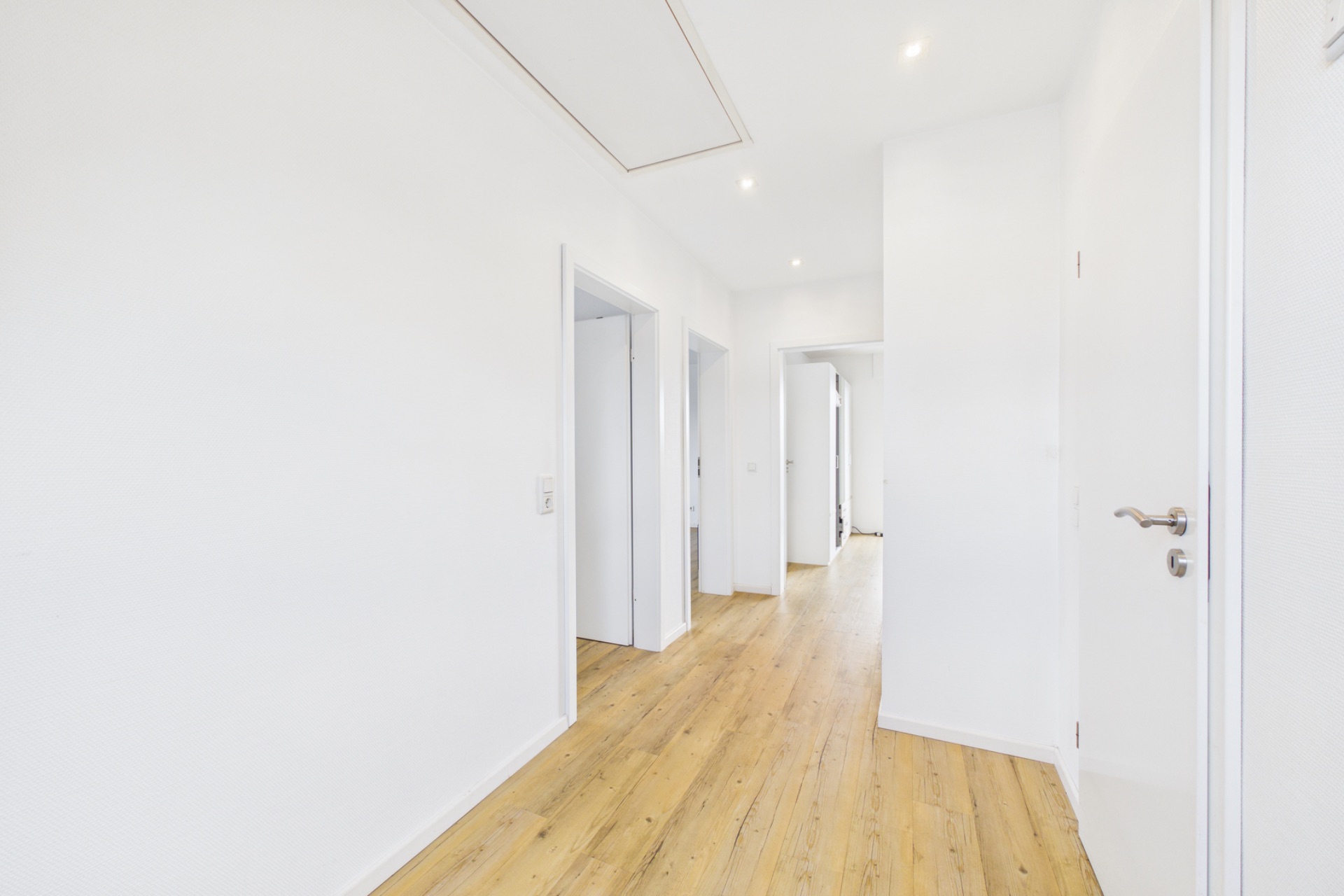 Heller Flur mit Holzboden und mehreren Türen in einer Wohnung.
