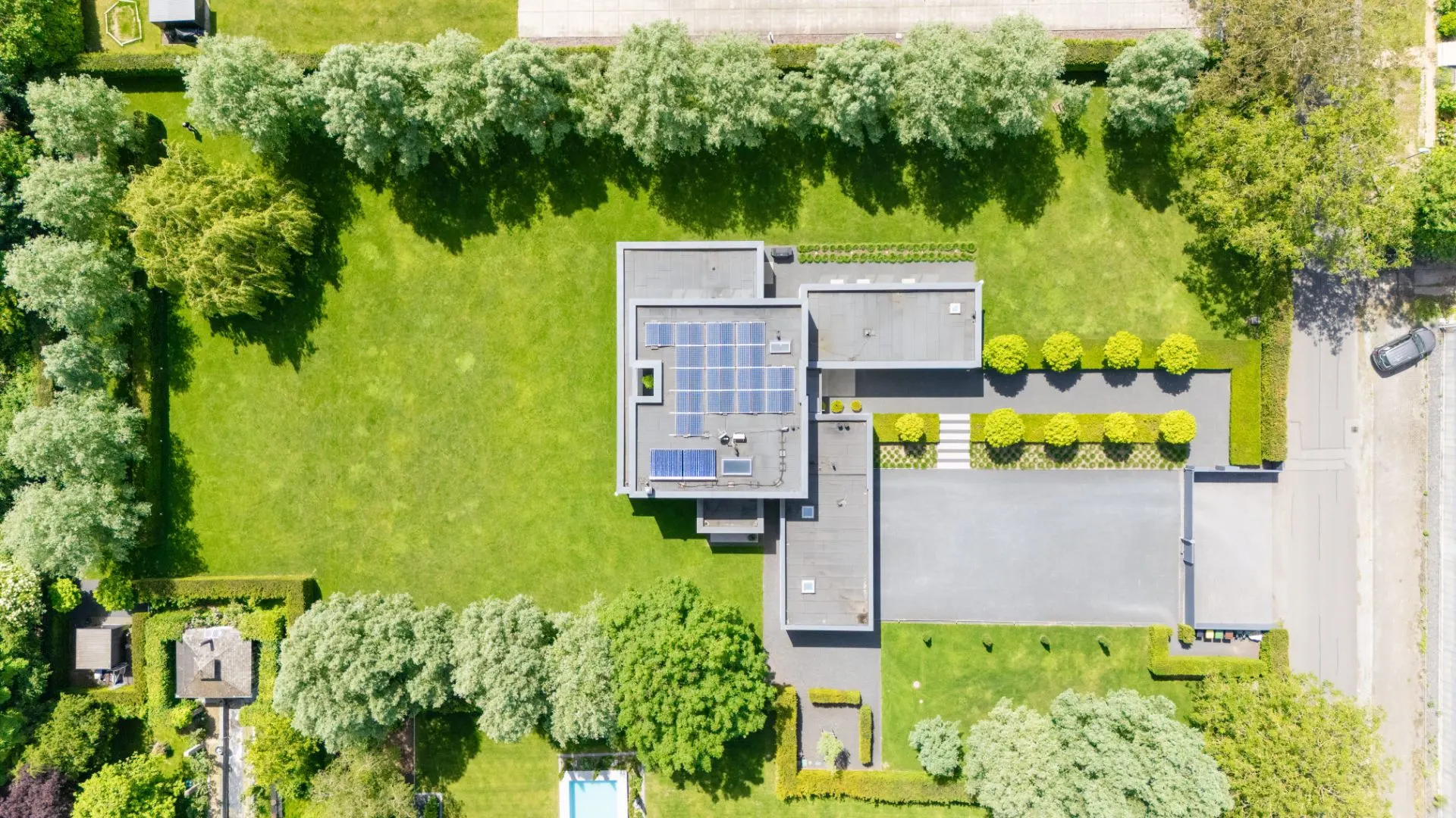 Luftaufnahme eines modernen Hauses mit Solarpanels und großem grünen Garten.
