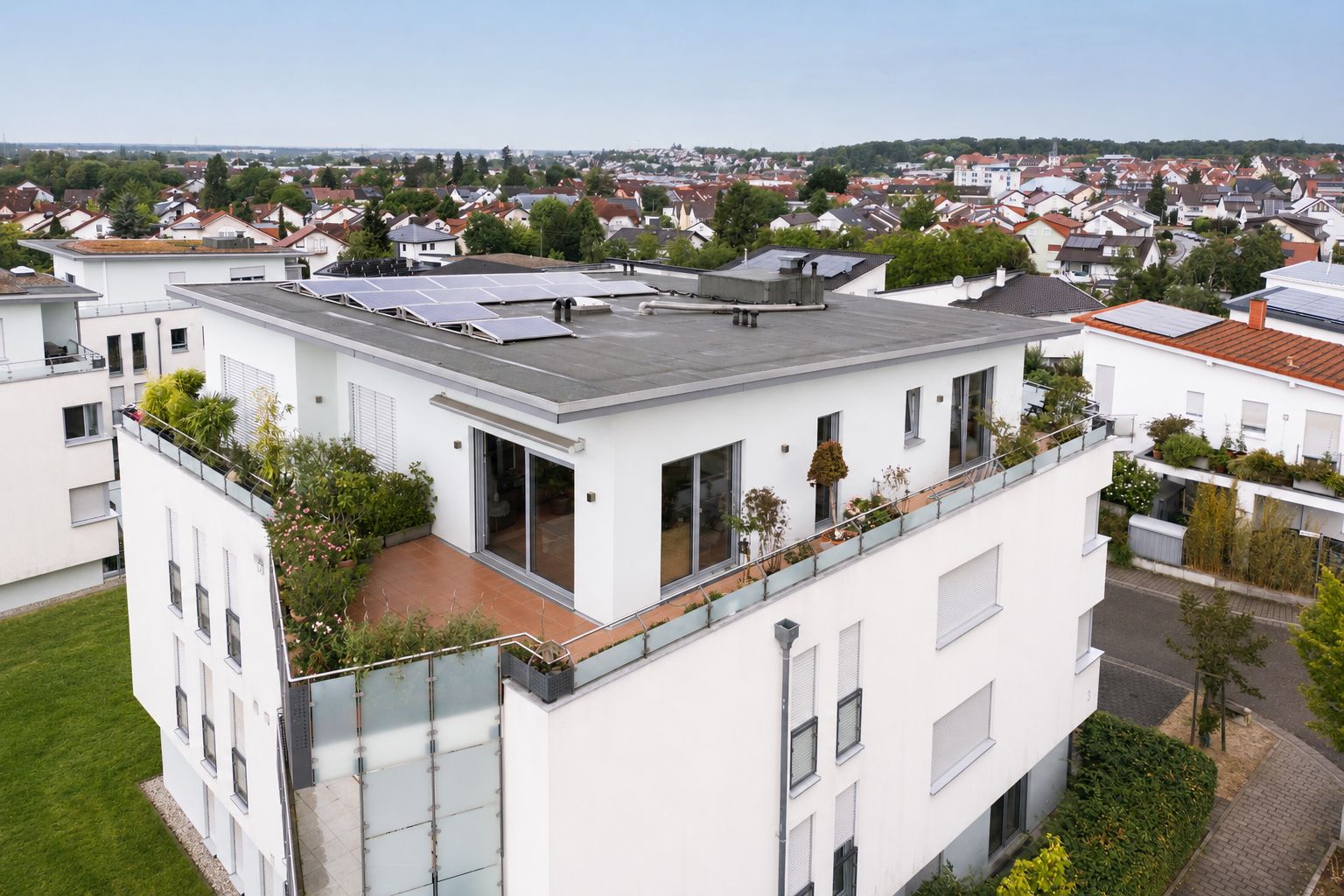Modernes Wohnhaus mit großer Dachterrasse und Solarpanelen auf dem Flachdach.