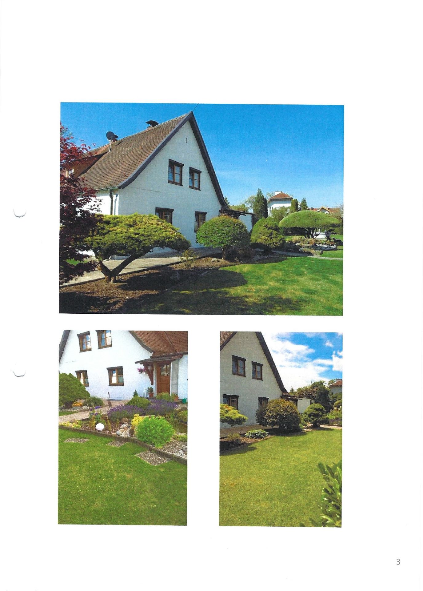 Weißes Einfamilienhaus mit gepflegtem Garten und Sträuchern bei sonnigem Wetter.