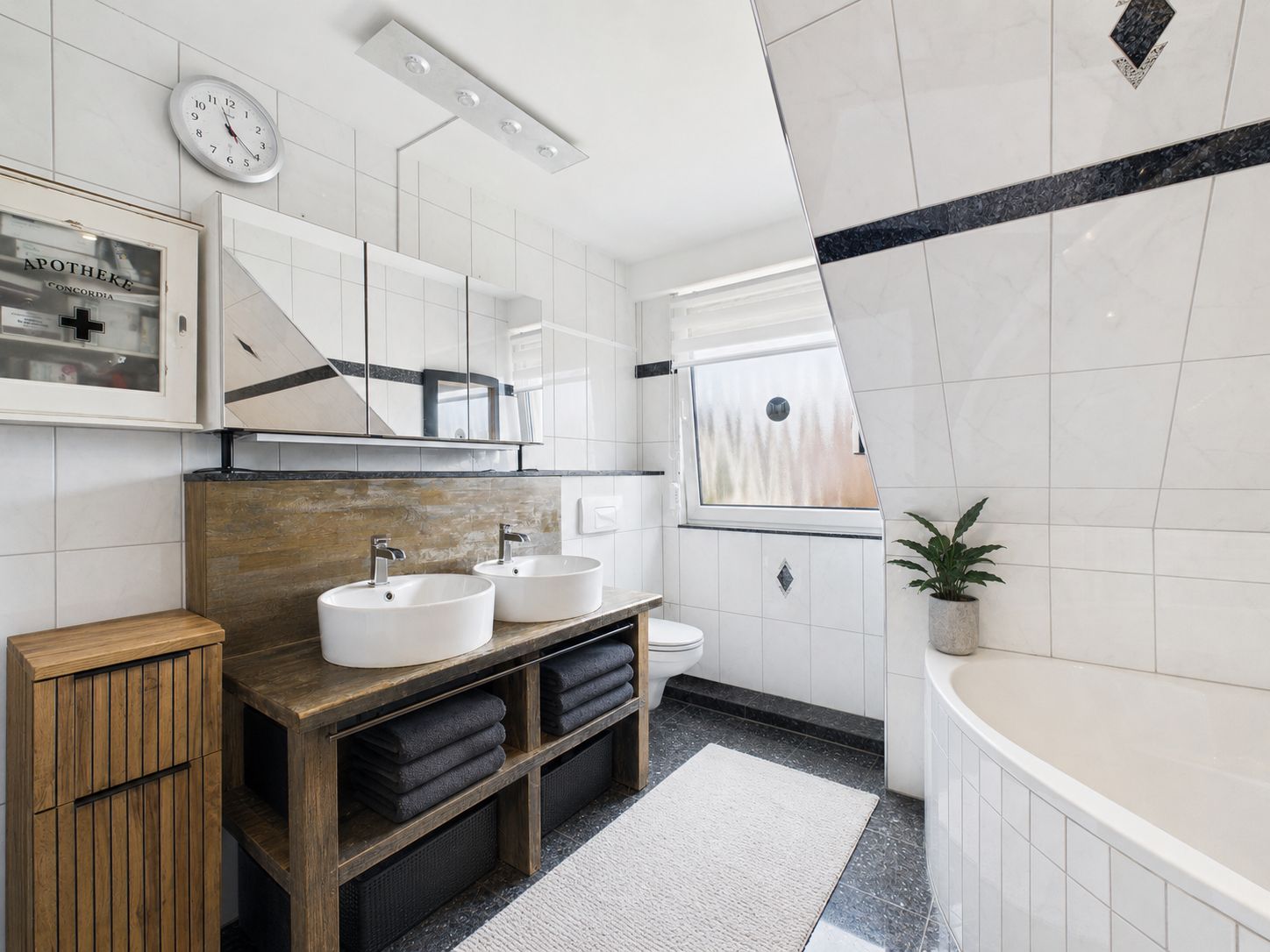 Modernes Badezimmer mit zwei Waschbecken, Spiegelschrank, Badewanne und Fenster.