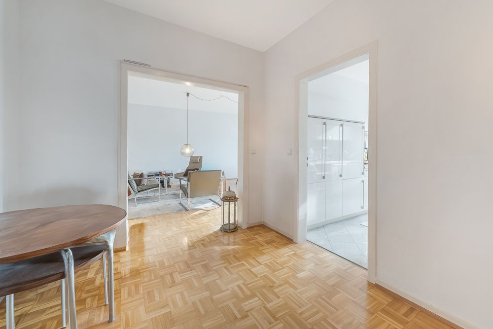 Heller Flur mit Holzboden, Zugang zu Wohnzimmer und Küche, runder Holztisch links.