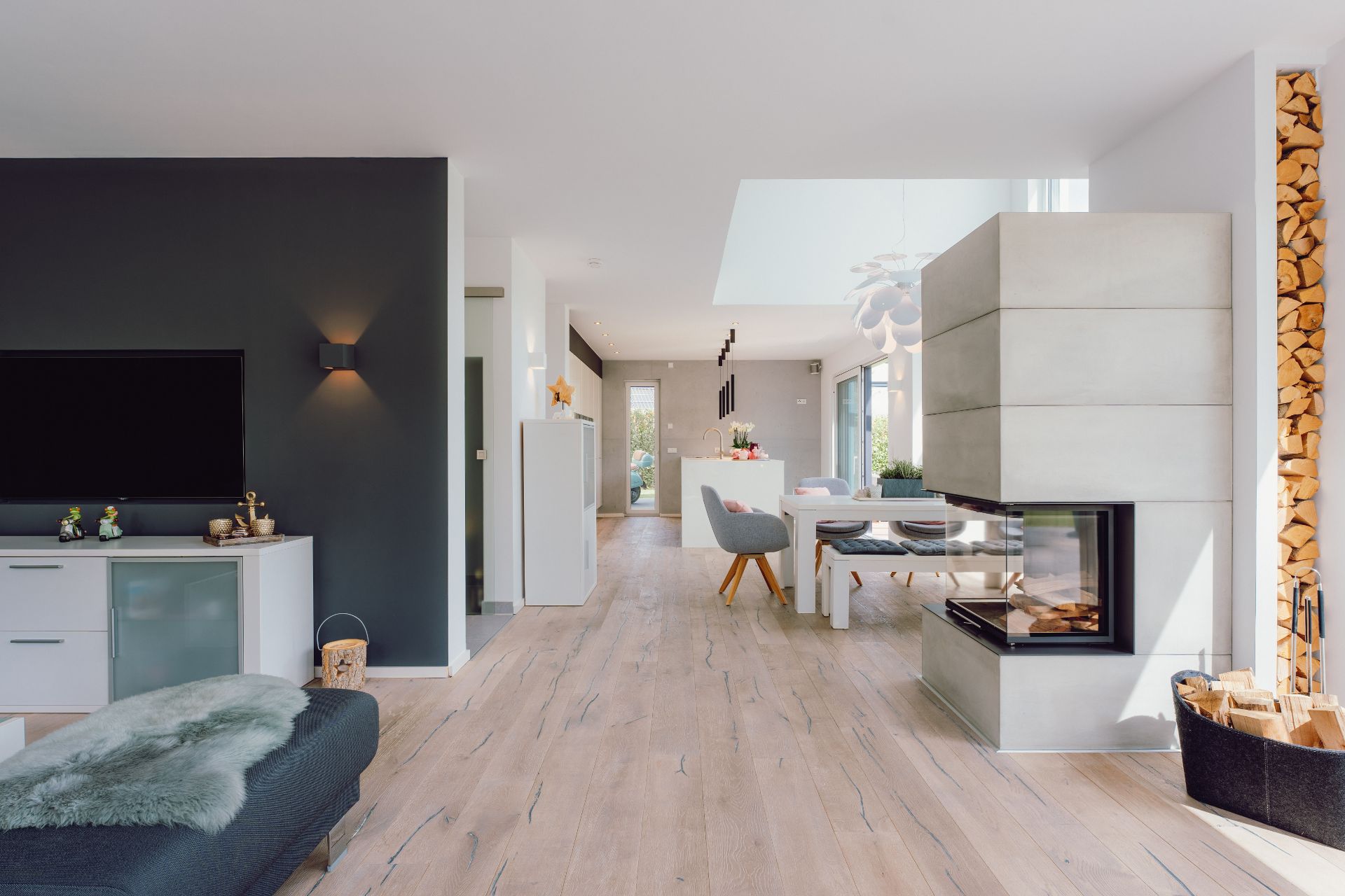 Modernes Wohnzimmer mit Kamin, Fernseher und Essbereich, hell und offen gestaltet.