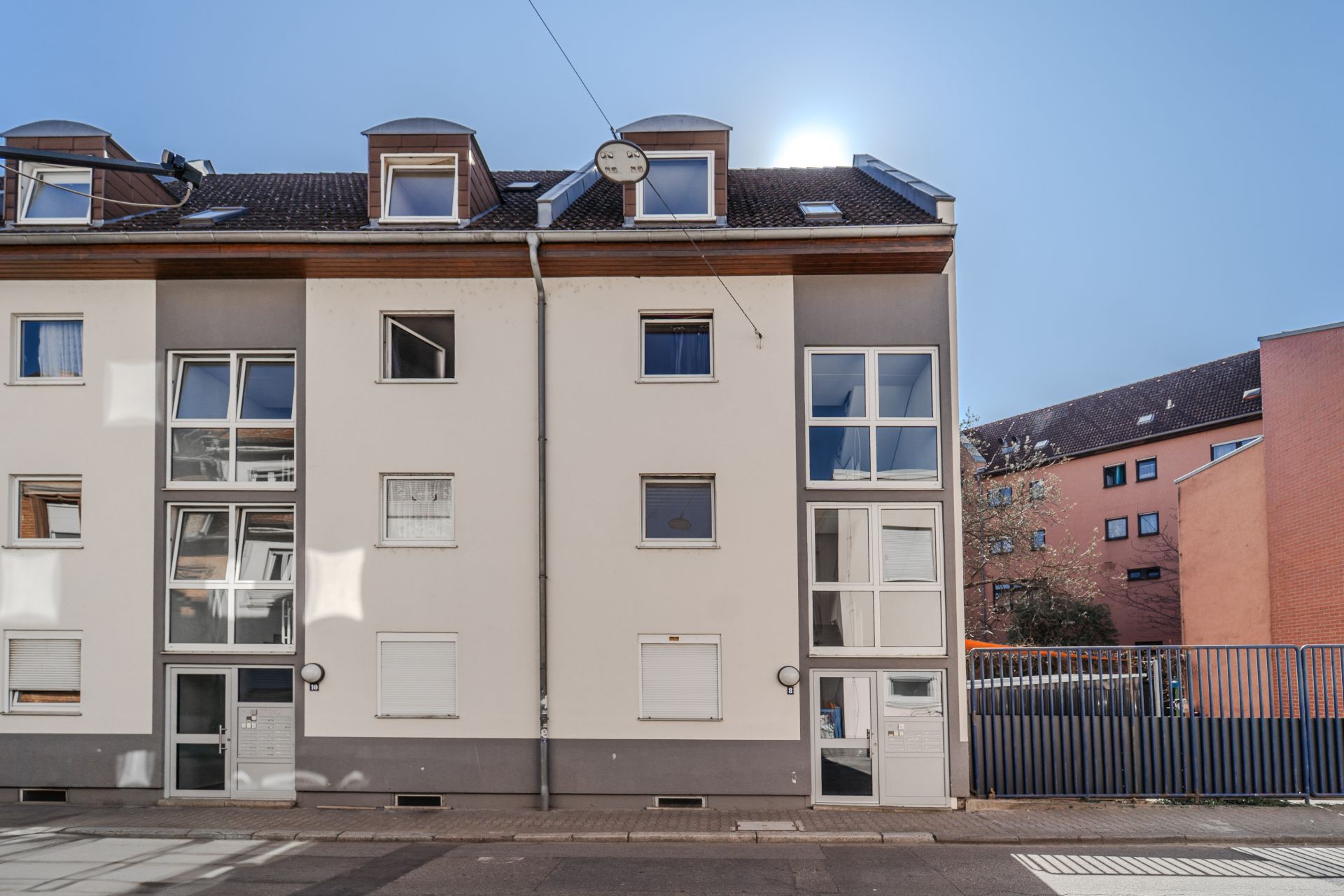 Außenansicht eines mehrstöckigen Wohnhauses mit großen Fenstern und Dachgauben.