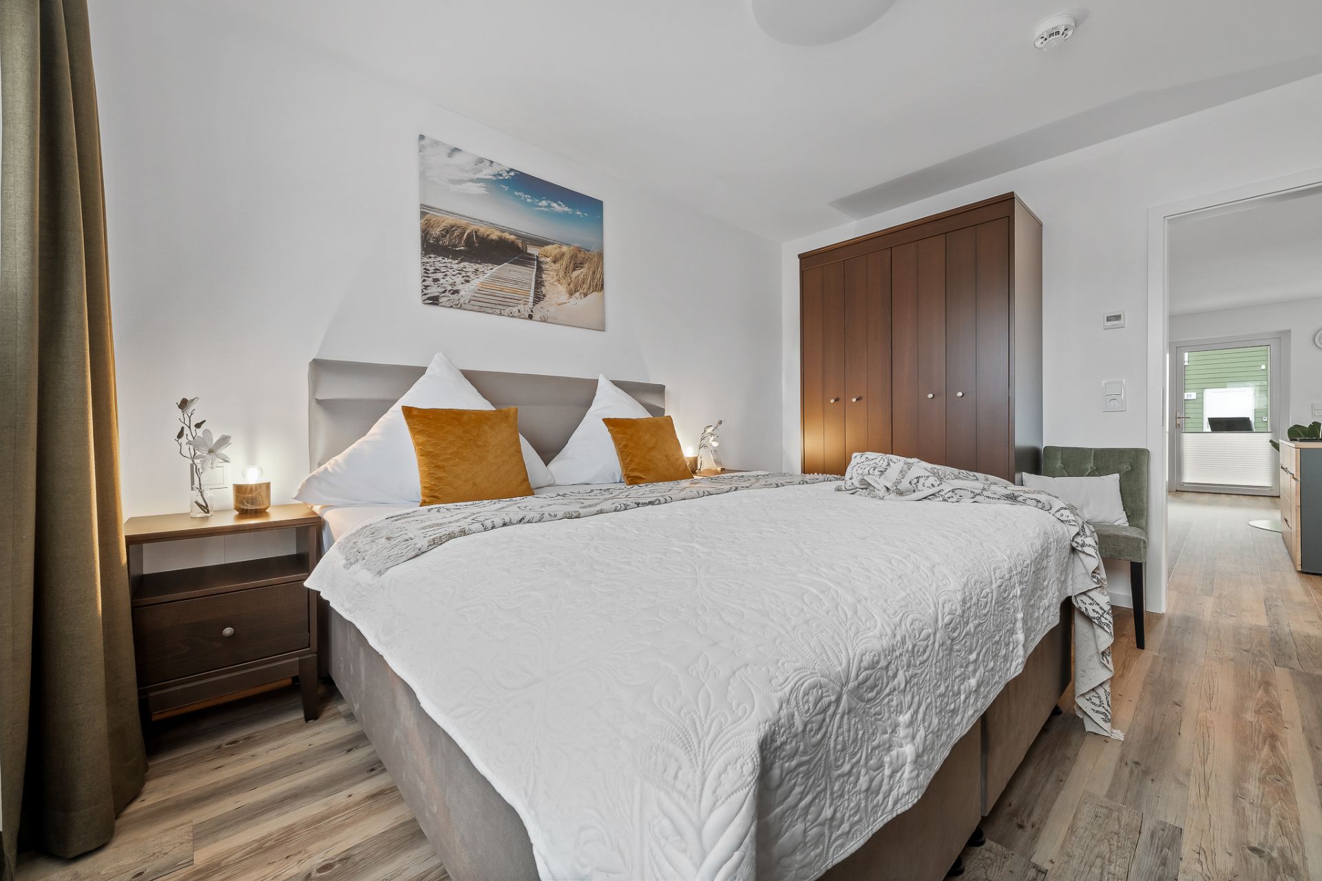 Helles Schlafzimmer mit Doppelbett, braunem Kleiderschrank und Nachttischen.