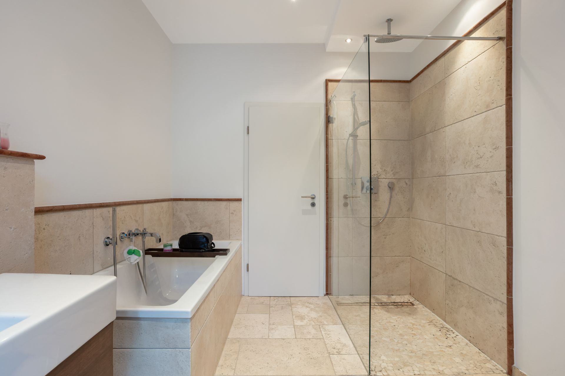Modernes Badezimmer mit Badewanne und offener Dusche mit Glaswand.