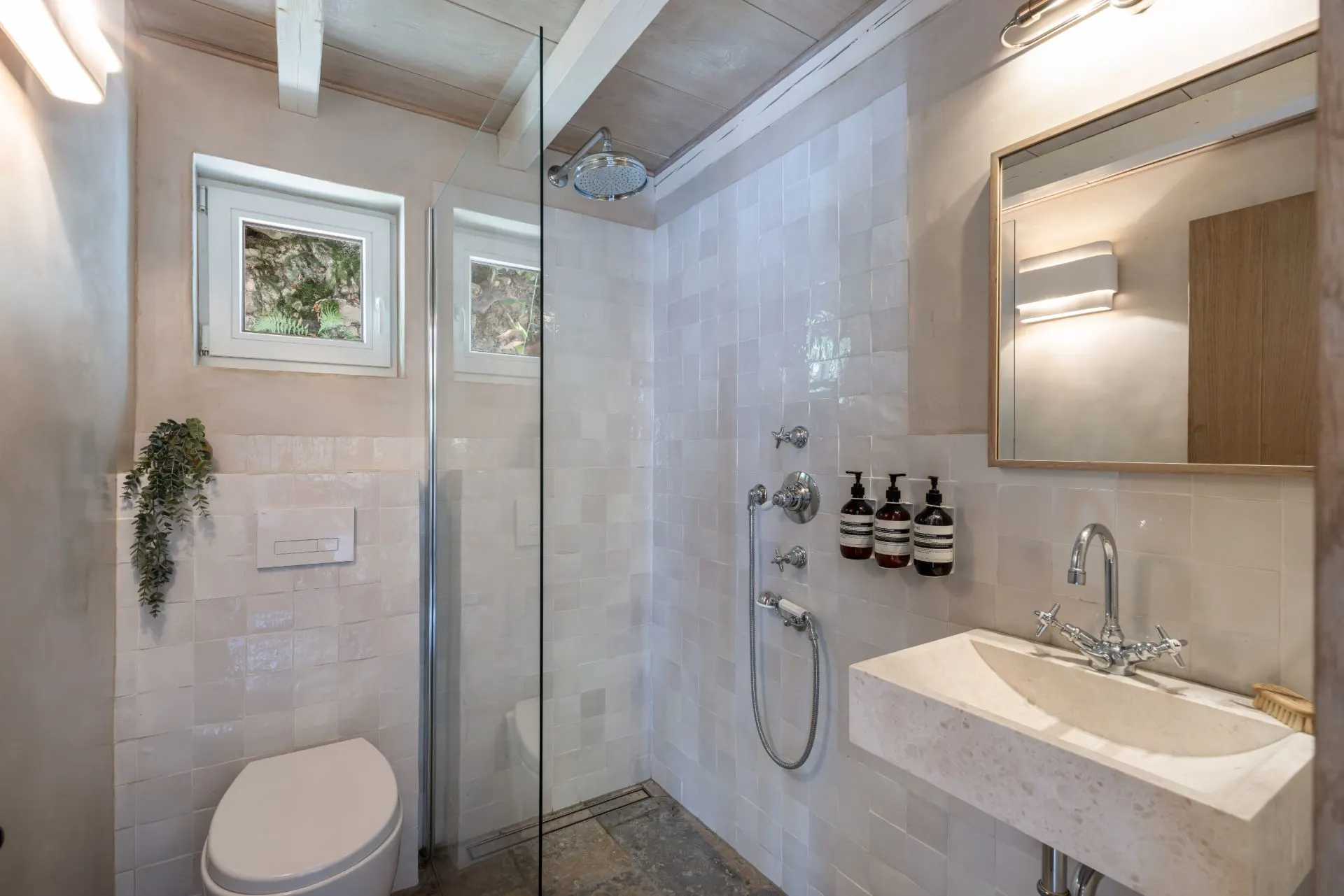 Modernes Badezimmer mit Dusche, Toilette, Waschbecken und zwei Fenstern.