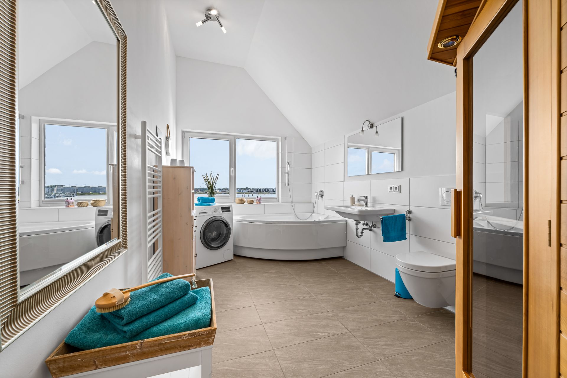 Helles Badezimmer mit Eckbadewanne, Waschmaschine, Spiegel, WC und Sauna.