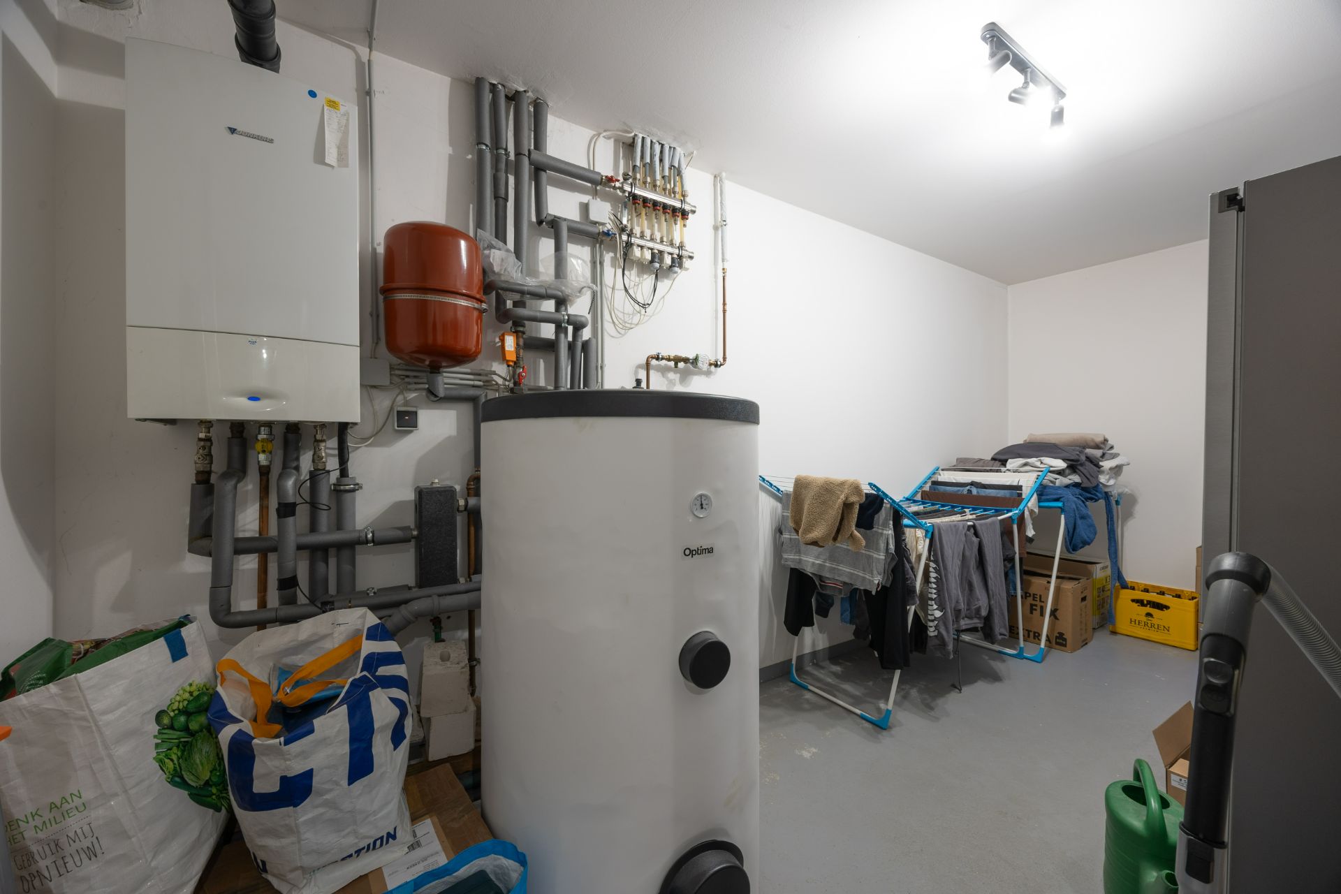 Hauswirtschaftsraum mit Heizanlage, Wasserboiler, Wäschegestell und Kartons.